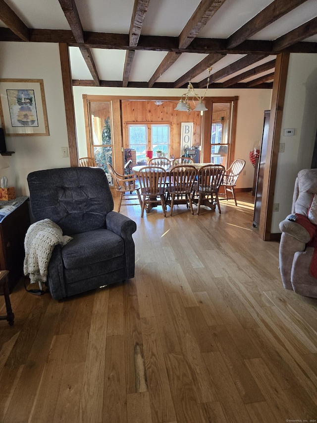 living room featuring beam ceiling, wood-type flooring, and a notable chandelier