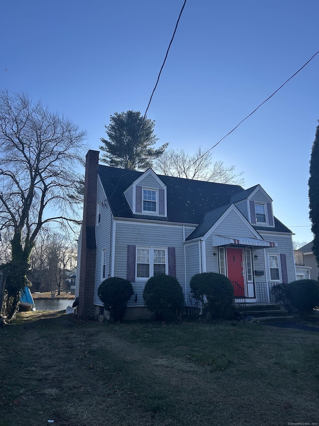 view of front of house featuring a chimney and a front yard