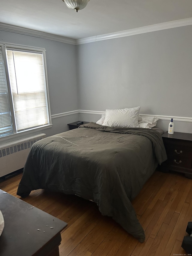 bedroom with crown molding, hardwood / wood-style floors, and radiator