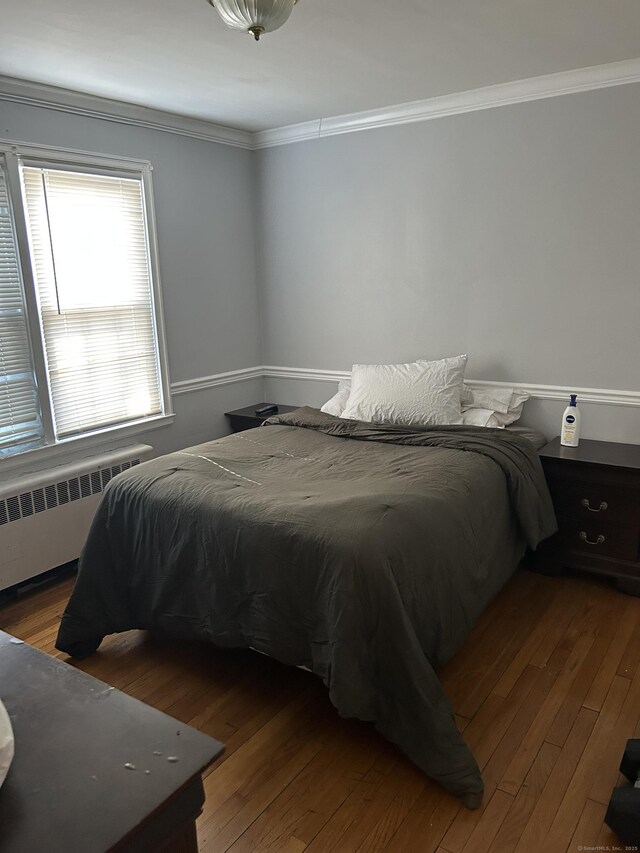 bedroom with radiator, hardwood / wood-style floors, and crown molding