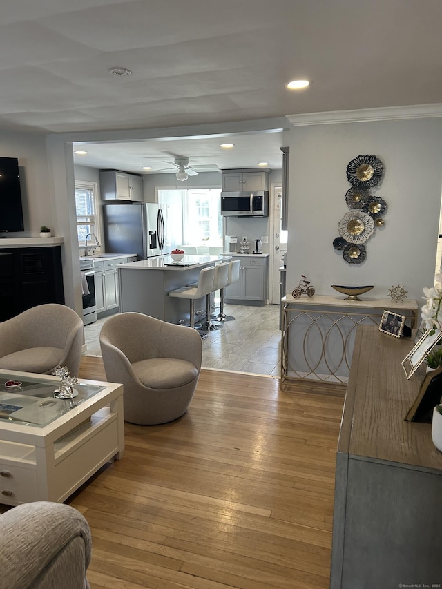 living area with crown molding, recessed lighting, light wood-type flooring, and ceiling fan