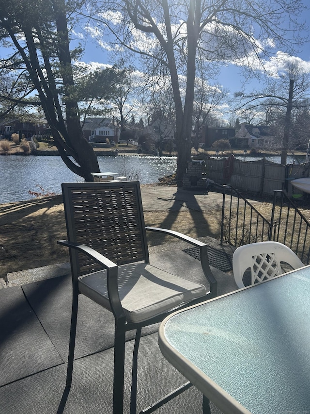 view of patio with a water view and fence