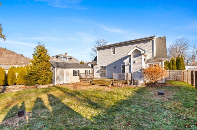 rear view of house with a lawn, a storage shed, and a deck