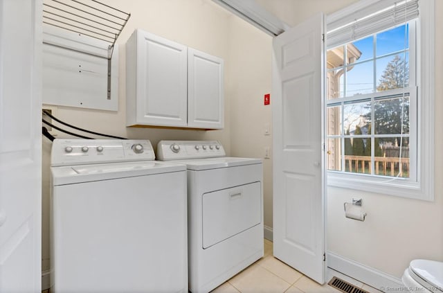 washroom with a healthy amount of sunlight, cabinets, light tile patterned floors, and independent washer and dryer