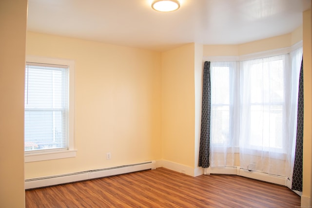 spare room featuring a baseboard radiator, a wealth of natural light, and hardwood / wood-style flooring