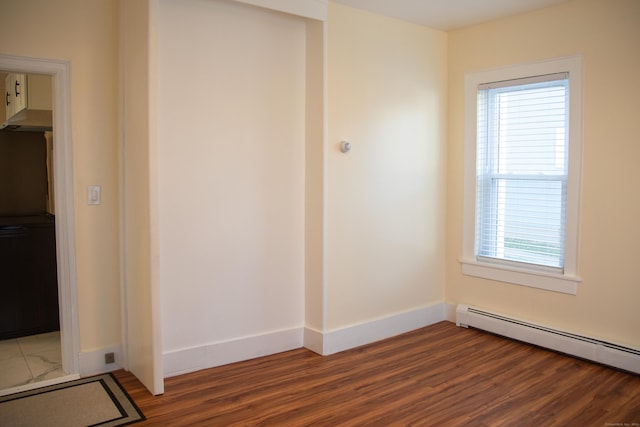 spare room featuring baseboard heating and dark wood-type flooring