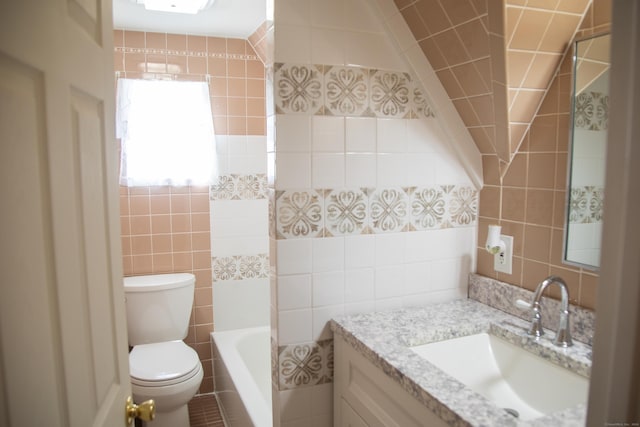 bathroom with a washtub, vanity, toilet, and tile walls