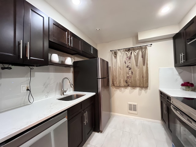 kitchen with appliances with stainless steel finishes, dark brown cabinetry, backsplash, and sink