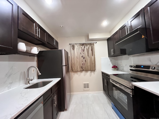 kitchen with dark brown cabinets, sink, stainless steel appliances, and tasteful backsplash