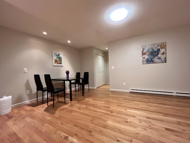 dining space with a baseboard heating unit and light wood-type flooring