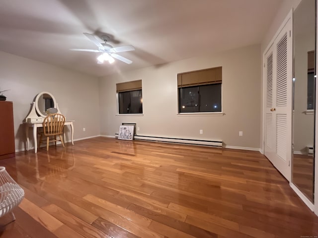 unfurnished bedroom with ceiling fan, a closet, a baseboard radiator, and hardwood / wood-style flooring