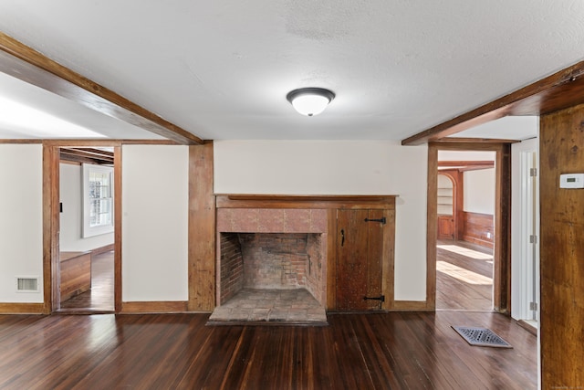 unfurnished living room with beamed ceiling, dark hardwood / wood-style flooring, and a textured ceiling