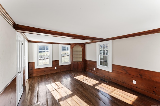 empty room featuring ornamental molding, wooden walls, dark hardwood / wood-style flooring, and beam ceiling