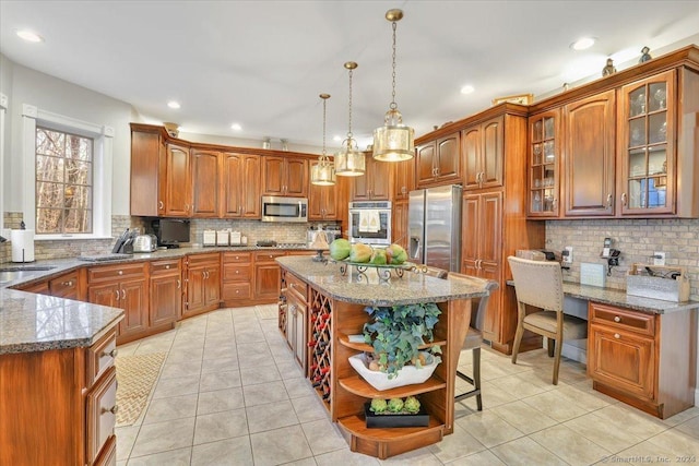 kitchen featuring sink, light stone counters, decorative light fixtures, a kitchen island, and appliances with stainless steel finishes