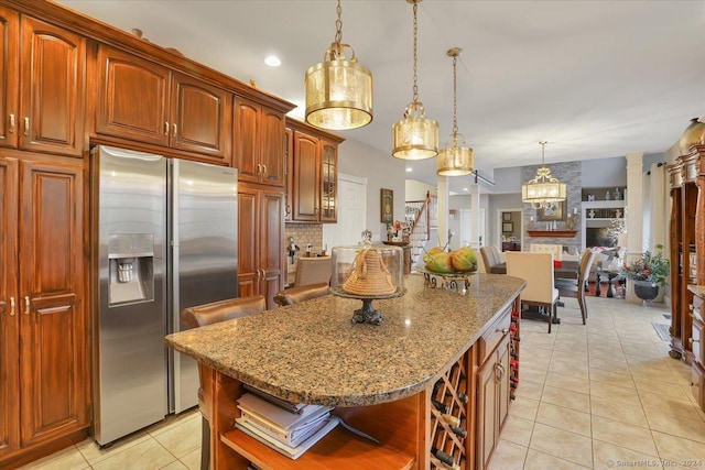 kitchen with light tile patterned floors, stainless steel fridge, pendant lighting, a kitchen bar, and a kitchen island