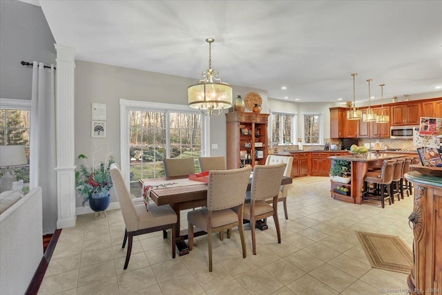 tiled dining room with a chandelier, ornate columns, and plenty of natural light