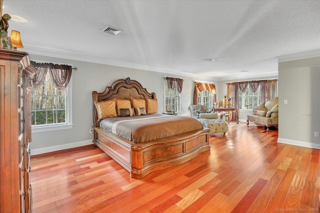 bedroom featuring light wood-type flooring, a textured ceiling, and ornamental molding