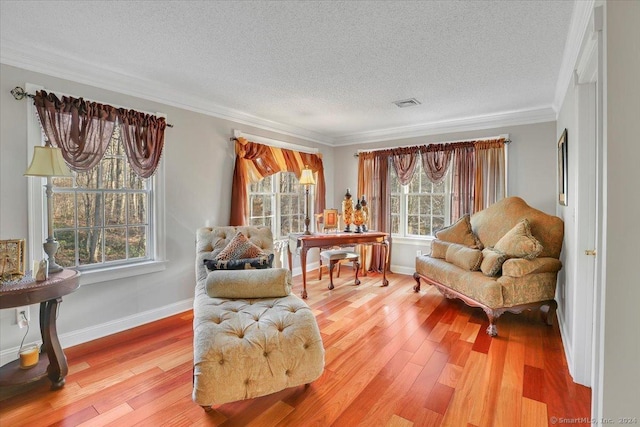 sitting room with crown molding, a healthy amount of sunlight, a textured ceiling, and wood-type flooring