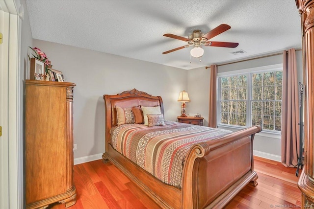 bedroom with ceiling fan, a textured ceiling, and light hardwood / wood-style flooring