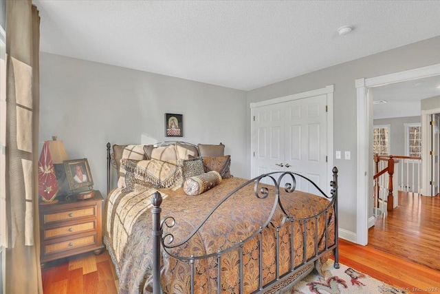 bedroom with a textured ceiling, light hardwood / wood-style flooring, and a closet