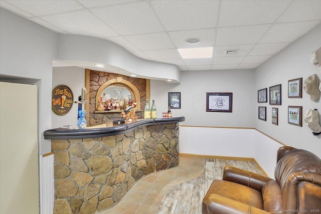 bar with hardwood / wood-style flooring and a drop ceiling