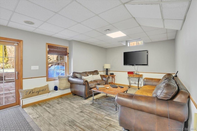 living room with a paneled ceiling and light hardwood / wood-style floors