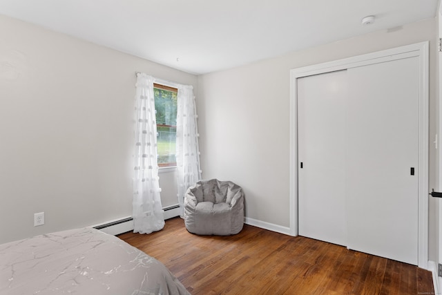 bedroom featuring wood-type flooring, a baseboard radiator, and a closet