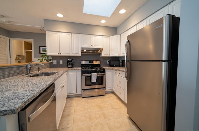 kitchen with sink, a skylight, tasteful backsplash, white cabinetry, and stainless steel appliances