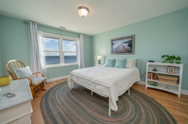 bedroom with a water view and wood-type flooring