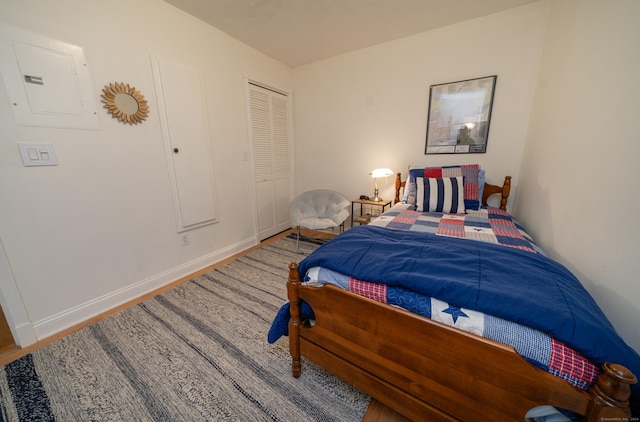 bedroom with electric panel, a closet, and hardwood / wood-style flooring