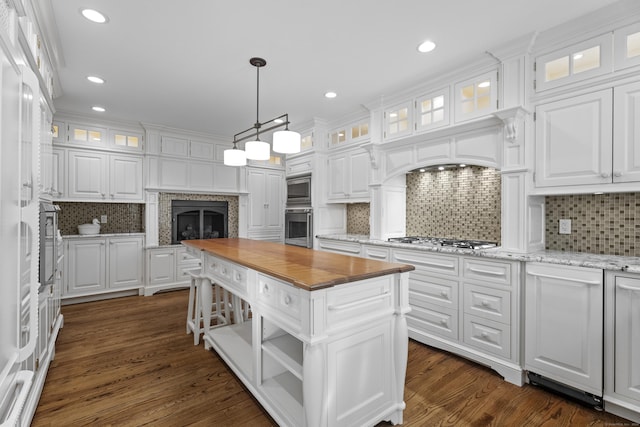 kitchen with white cabinets, a center island, stainless steel appliances, and wooden counters