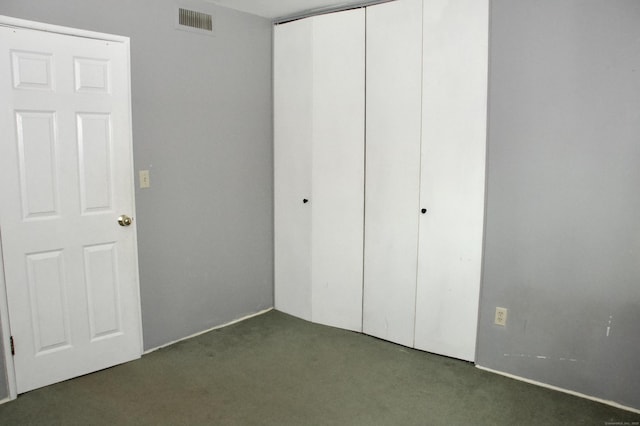 unfurnished bedroom featuring dark colored carpet and a closet