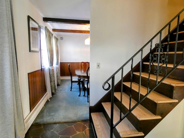 staircase with a baseboard radiator and beam ceiling