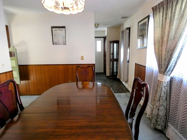 dining room with a chandelier and wood walls