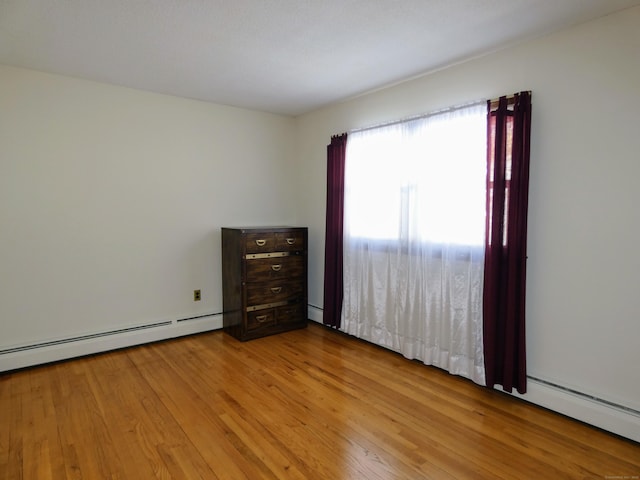 unfurnished bedroom featuring a baseboard heating unit and light hardwood / wood-style flooring