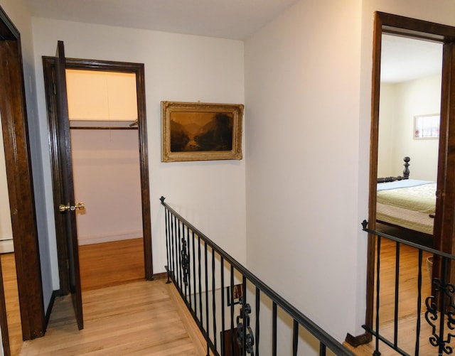 hall with a baseboard heating unit and light hardwood / wood-style floors