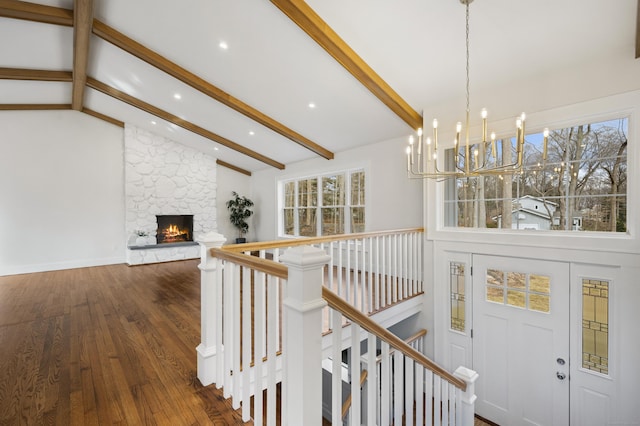 stairs with a fireplace, lofted ceiling with beams, a notable chandelier, and hardwood / wood-style flooring