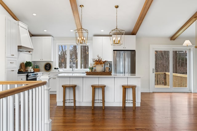 kitchen with white cabinets, appliances with stainless steel finishes, a center island, and a kitchen breakfast bar