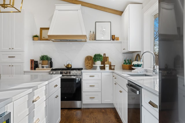 kitchen with custom exhaust hood, white cabinets, sink, light stone counters, and stainless steel appliances