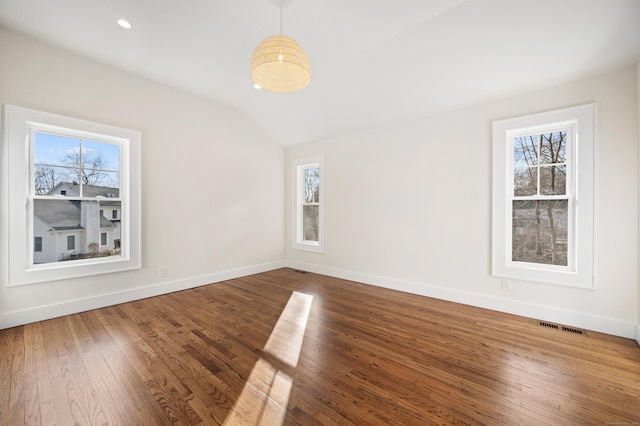 spare room with hardwood / wood-style floors and vaulted ceiling