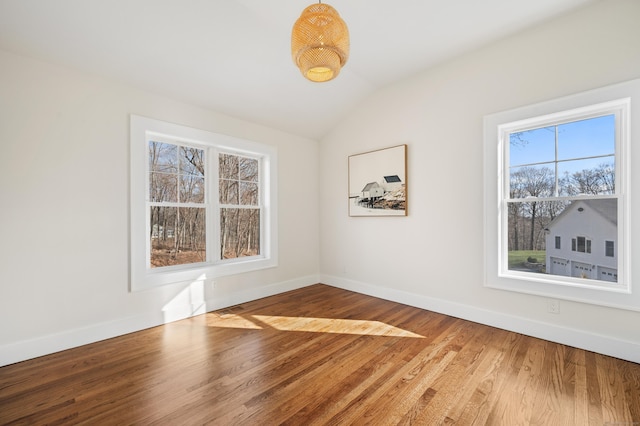 spare room featuring wood-type flooring and vaulted ceiling