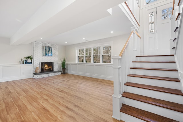 stairway featuring hardwood / wood-style flooring and a brick fireplace