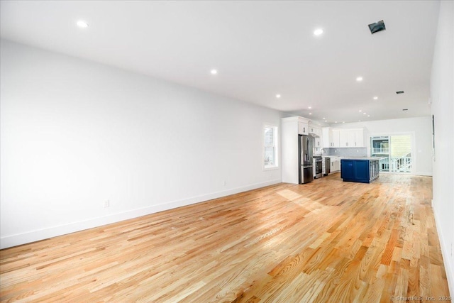 unfurnished living room with light hardwood / wood-style floors and a healthy amount of sunlight