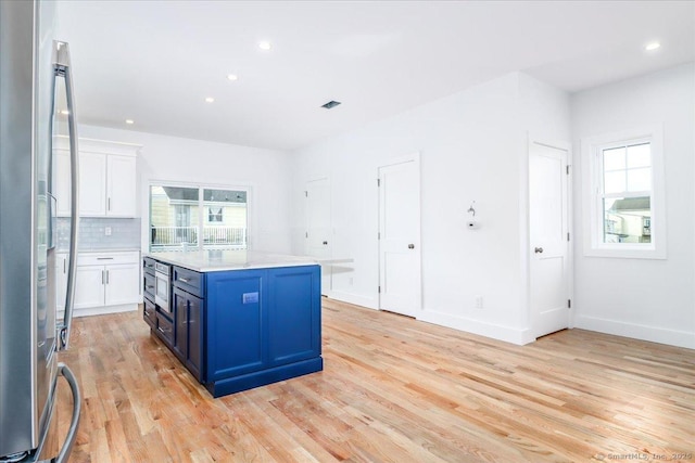 kitchen with blue cabinetry, plenty of natural light, a kitchen island, and white cabinets