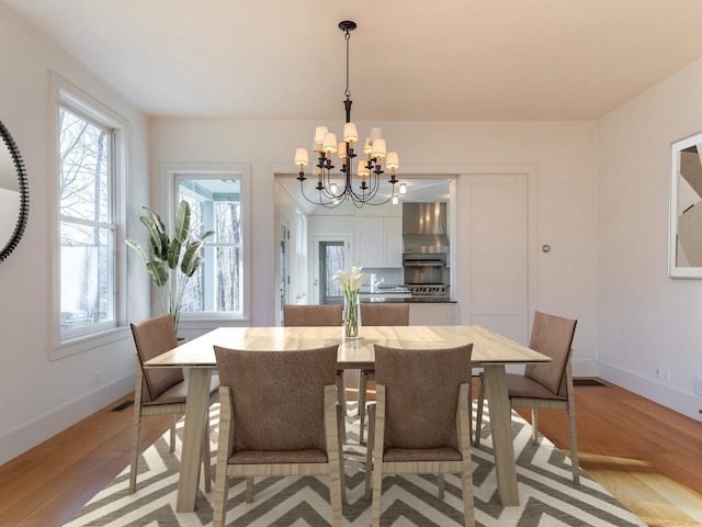 dining space featuring a notable chandelier and light wood-type flooring