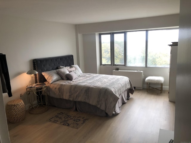 bedroom featuring radiator heating unit and light wood-type flooring