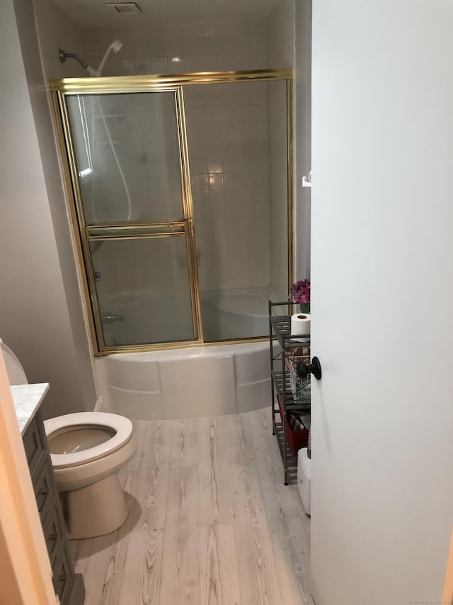 full bathroom with hardwood / wood-style flooring, vanity, toilet, and combined bath / shower with glass door