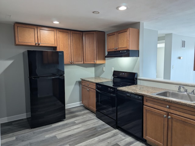 kitchen featuring light stone countertops, sink, light hardwood / wood-style flooring, and black appliances