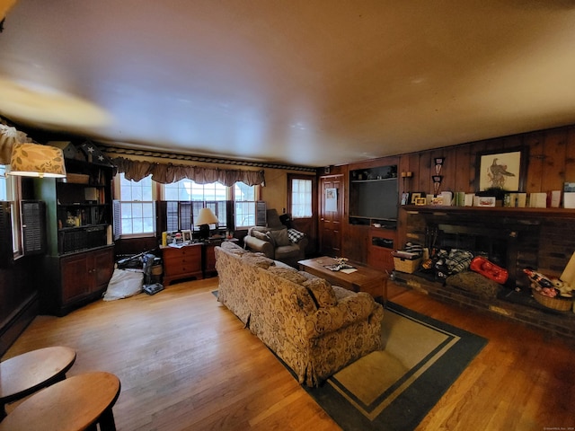 living room with light hardwood / wood-style flooring and wood walls