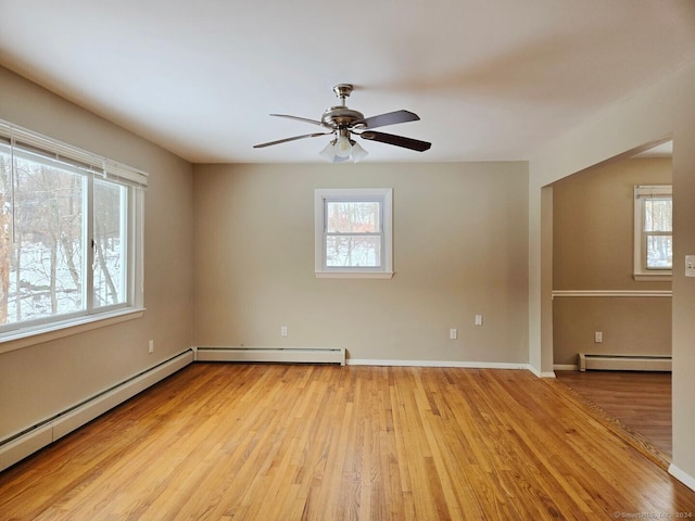 unfurnished room featuring ceiling fan, baseboard heating, and light hardwood / wood-style flooring